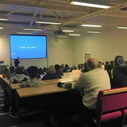 A lecture theater full of students watching the presentation given by Bloc Digital.
