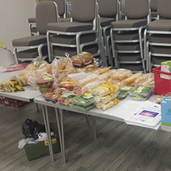 Fresh foods or baked goods which will go out of date quickly are displayed on a table for people to take.