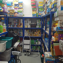 One of two wearehouses at the food bank. The shelves around the edges are piled with tins, boxes of cereal and various food.